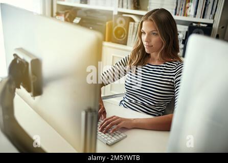 Den Ball am Laufen halten. Aufnahmen aus dem hohen Winkel einer schönen jungen Frau, die von zu Hause aus arbeitet. Stockfoto