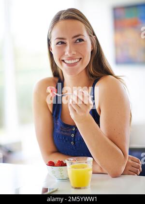 Sie hat etwas Süßes im Kopf... eine junge Frau, die zu Hause eine Schüssel Erdbeeren isst. Stockfoto