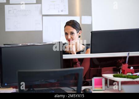 Sie ist ein motivierter Mitarbeiter. Eine Frau, die an ihrem Arbeitsplatz in einem Büro sitzt. Stockfoto