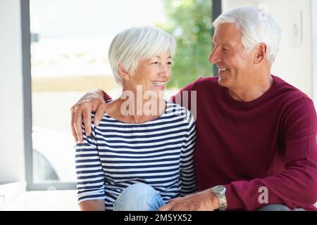 Was wollen wir mehr, wenn wir uns haben? Ein liebevolles Seniorenpaar, das zu Hause zusammensitzt. Stockfoto