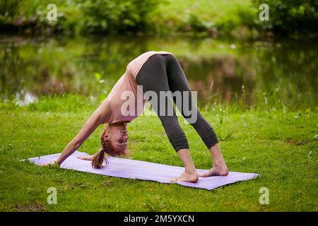 Sie balanciert ihren Körper und ihre Seele. Eine Frau, die im Park Yoga macht. Stockfoto