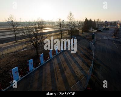 Die Morgensonne scheint durch eine neu installierte, noch im Bau befindliche Tesla Supercharger EV-Ladestation für den beliebten amerikanischen Autohersteller. Stockfoto