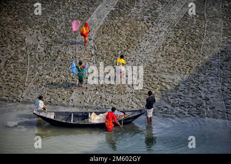 Die Familie der Fischer kehrt nach dem Angeln auf dem Fluss Matla nach Hause zurück. Die Konservenfabrik befindet sich fast 100 km von Kalkutta entfernt und befindet sich in der Gegend unter dem Sunderban-Delta am westlichen Ufer des Flusses Matla. Die meisten Bewohner des Deltas sind Fischer, die vor Herausforderungen stehen, da der Ozean Land im weltweit größten Mangrovenwald verschluckt, Menschen und Tiger in eine immer kleiner werdende Fläche in den indischen Sundarbans gedrängt werden, mit tödlichen Folgen. Der Meeresspiegel ist in den letzten zwei Jahrzehnten in den Sundarbans um durchschnittlich 3 bis 5 Zentimeter pro Jahr gestiegen, was zu einer der schnellsten Küstenraten führt Stockfoto