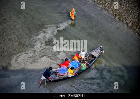 Die Familie der Fischer kehrt nach dem Angeln auf dem Fluss Matla nach Hause zurück. Die Konservenfabrik befindet sich fast 100 km von Kalkutta entfernt und befindet sich in der Gegend unter dem Sunderban-Delta am westlichen Ufer des Flusses Matla. Die meisten Bewohner des Deltas sind Fischer, die vor Herausforderungen stehen, da der Ozean Land im weltweit größten Mangrovenwald verschluckt, Menschen und Tiger in eine immer kleiner werdende Fläche in den indischen Sundarbans gedrängt werden, mit tödlichen Folgen. Der Meeresspiegel ist in den letzten zwei Jahrzehnten in den Sundarbans um durchschnittlich 3 bis 5 Zentimeter pro Jahr gestiegen, was zu einer der schnellsten Küstenraten führt Stockfoto