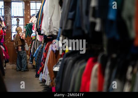 Ein Mitarbeiter organisiert Kleidung zum Verkauf im Traid Charity Shop in Dalston, East London. Traid, eine Wohltätigkeitsorganisation, die sich dafür einsetzt, dass Kleidung nicht weggeworfen wird, hat 2022 3.222 Tonnen Kleidung aus der Mülldeponie und der Verbrennung abgezweigt, die CO2-Emissionen um 30.609 Tonnen gesenkt und mehr als 11,2 Millionen Kleidungsstücke wieder in Betrieb genommen. Foto: Freitag, 25. November 2022. Stockfoto