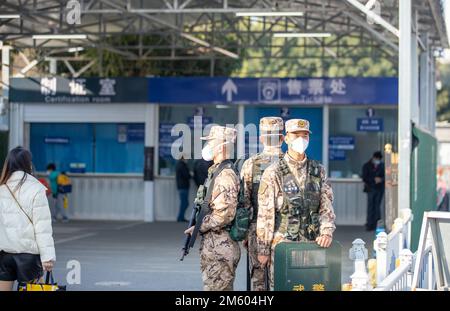 BEIHAI, CHINA - 1. JANUAR 2023 - bewaffnete Polizeibeamte stehen an einem Ticketschalter an einem Bahnhof in Beihai, Südchina Guangxi Zhuan, Wache Stockfoto