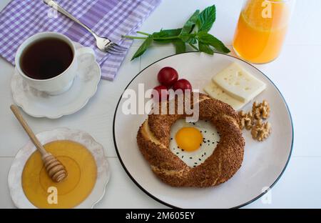 Köstlicher Frühstücksteller, Frühstückspräsentation bestehend aus Bagels, Eiern, Käse, Orangensaft, Tee, Walnüsse und Tomaten. Stockfoto