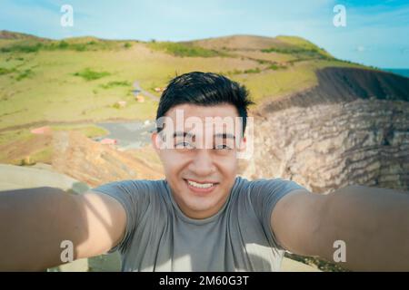 Ein abenteuerlustiger Mann macht ein Selfie an einem Aussichtspunkt. Nahaufnahme einer Person, die ein Abenteuer-Selfie macht, ein Tourist, der ein Selfie an einem Aussichtspunkt macht. Gut Aussehend Stockfoto