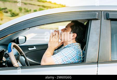 Nahaufnahme eines Fahrers, der in seinem Fahrzeug betet, und eines Mannes, der in seinem Fahrzeug betet, bevor er abfährt. Das Konzept des Fahrers, der mit den Händen zusammen meditiert Stockfoto