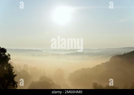 Blick über Täler und bewaldete Höhen im aufgehenden Morgennebel mit Morgensonne, Naturpark Arnsberg-Wald, Nordrhein-Westfalen, Deutschland Stockfoto