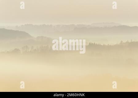 Blick über Täler und bewaldete Höhen in dichtem Nebel am frühen Morgen, Naturpark Arnsberg-Wald, Nordrhein-Westfalen, Deutschland Stockfoto