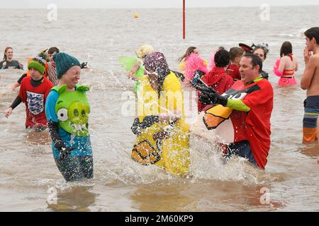 Lyme Regis, Dorset, Großbritannien. 1. Januar 2023 Hunderte von Neujahrsfeierern in schicken Kleidern, beobachtet von riesigen Menschenmassen, nehmen an einem bedeckten feuchten Tag am jährlichen Lyme Lunge-Schwimmen im Lyme Regis in Dorset Teil, um Mencap und der National Heart Foundation zu helfen. Bildnachweis: Graham Hunt/Alamy Live News Stockfoto