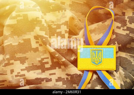 Pixeliges digitales Tarnmaterial mit ukrainischer Flagge und Wappen auf Chevron in Blau und Gelb. Attribute der ukrainischen Soldatenuniform Stockfoto