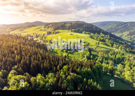 Albrechtice V Jizerskych Horach Stadt inmitten der grünen Hügel des Jizera Gebirges am sonnigen Sommertag. Tschechische Republik. Luftaufnahme von der Drohne. Stockfoto