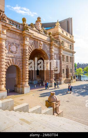 STOCKHOLM, SCHWEDEN - 10. JUNI 2022: Menschen, die in den Straßen von Stockholm durch das Parlamentsgebäude gehen, Schwedisch: Riksdagshuset, Gate, Stockholm, Schweden Stockfoto