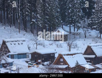 Steile Dächer mit Schnee bedeckt in Bergdorf mit Wäldern Stockfoto