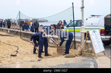 Brighton UK 1. Januar 2023 - Mitglieder des Royal Navy Bomb Disposal Teams sammeln Sand vom Brighton Beach Volleyballplatz, um mit einer WW2-Muschel zu helfen, die östlich des Palace Pier weiter am Strand angespült wurde : Credit Simon Dack / Alamy Live News Stockfoto