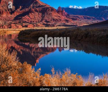 Unberührte Reflexion der Fishers Towers und der schneebedeckten La Sal Berge im Colorado River bei Moab, Utah Stockfoto