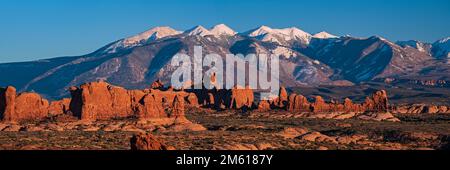 Abendpanorama des Windows Arch-Abschnitts des Arches-Nationalparks mit den schneebedeckten La Sal Mountains in der Ferne Stockfoto