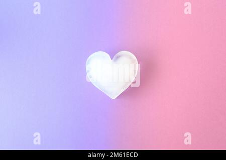 Eiskaltes Herz auf einer Kombination aus lila und pinkfarbenen Hintergrundfarben. Valentinseis lieben ästhetisches Konzept. Lebendige Farben. Stockfoto
