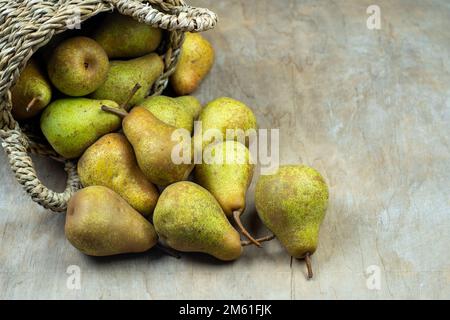 Birnen im Korb auf einem hölzernen Hintergrund. Obsternte. Stillleben im Herbst. Pear Variety Bera Konferenz. Vitaminfutter. Stockfoto