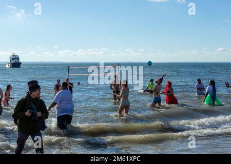 Brooklyn, New York, USA. 1. Januar 2023. Tausende von Badenden und Zuschauern erschienen an einem sonnigen und warmen Neujahrstag für den jährlichen Polarbärsprung auf Coney Island, gesponsert von der Alliance for Coney Island. Eine Gruppe von Leuten spielte Volleyball im Wasser, bis sie von Wachen angehalten wurden. Kredit: Ed Lefkowicz/Alamy Live News Stockfoto