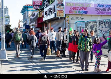 Brooklyn, New York, USA. 1. Januar 2023. Tausende von Badenden und Zuschauern erschienen an einem sonnigen und warmen Neujahrstag für den jährlichen Polarbärsprung auf Coney Island, gesponsert von der Alliance for Coney Island. 45 Minuten nach Beginn des Absturzes erstreckte sich die Anmeldelinie zwei Häuserblocks, die Stillwell Avenue hinauf und entlang der Surf Avenue zur West 12. Street. Kredit: Ed Lefkowicz/Alamy Live News Stockfoto