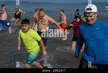 Racine, Wisconsin, USA. 1. Januar 2023. Die Temperaturen waren relativ mild für den 30. Jährlichen Splash and Dash Polar Sprung in Lake Michigan in Racine, Wisconsin Sonntag, den 1. Januar 2023. Die Lufttemperatur lag bei den niedrigen 40s Grad und die Wassertemperatur bei 36,9 Grad. Viele Jahre gibt es Eisplatten auf dem Sand von North Beach, die zum Wasser führen. Die Veranstaltung kommt mehreren lokalen Wohltätigkeitsorganisationen zugute. Kredit: ZUMA Press, Inc./Alamy Live News Stockfoto