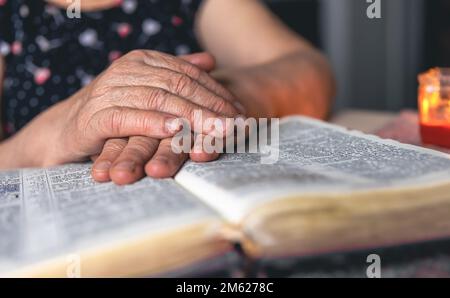 Eine alte Frau liest die Bibel, die Hände sind dicht. Stockfoto