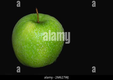 Grüner Apfel in Wassertropfen auf schwarzem Hintergrund isoliert. Stockfoto