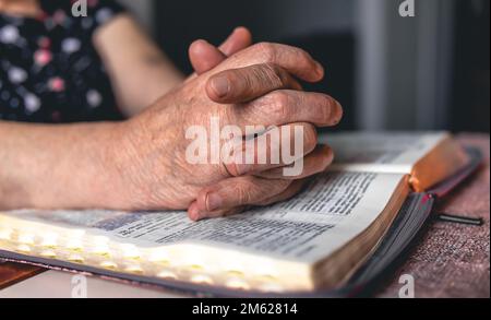 Eine alte Frau liest die Bibel, die Hände sind dicht. Stockfoto