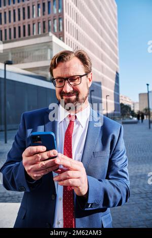Ein cooler Geschäftsmann, der das Mobile im Freien benutzt Stockfoto