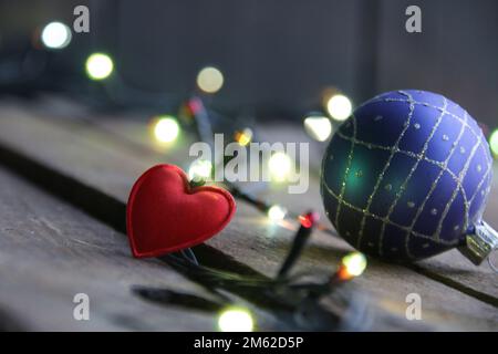 Frohe Weihnachtskarte. Rote Herz- und Weihnachtslichter auf altem Hintergrund. Stockfoto