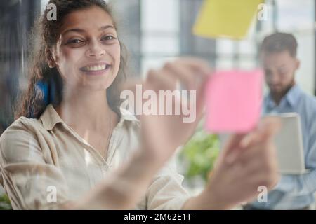Ihre Vision zum Leben erwecken. Aufnahme einer selbstbewussten Geschäftsfrau, die ihrem Kollegen mit Haftnotizen an einer Glaswand im Büro eine Idee vorstellt. Stockfoto