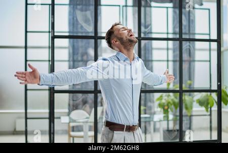 Porträt mit Kopfschuss und lächelndem selbstbewusstem Geschäftsmann im modernen Büro Stockfoto