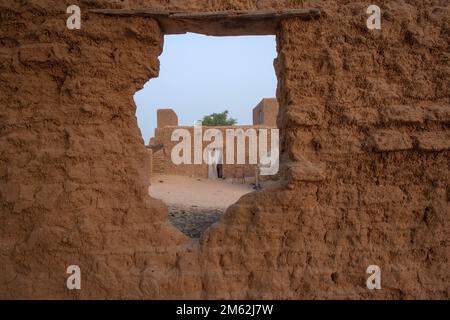 Blick auf das lehmhaus durch ein Loch in einer lehmwand in Timbuktu, Mali, Westafrika Stockfoto