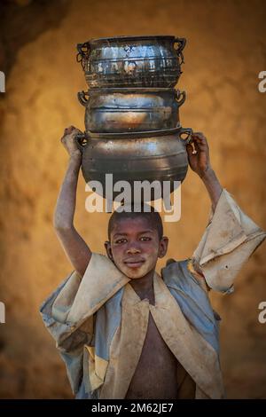 Kleiner Junge mit Töpfen auf seinem Niafunke head.in in Mali, Westafrika. Stockfoto