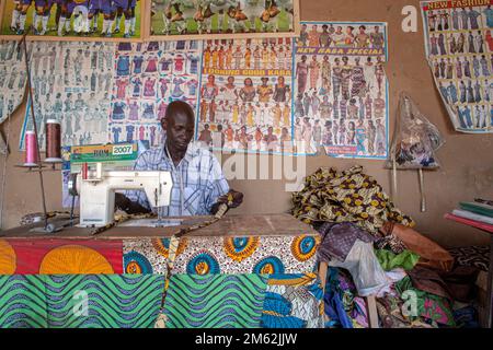 Porträt eines jungen afrikanischen Schneiders mit seiner Nähmaschine in Bamako , Mali , Westafrika . Stockfoto