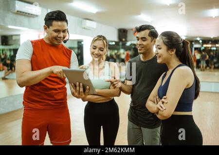 Gruppe junger Athleten und männlicher Lehrer mit einem Pad Stockfoto