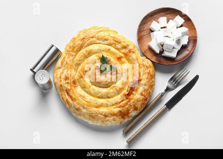 Köstlicher Käsekuchen und Teller mit Feta auf grauem Hintergrund Stockfoto