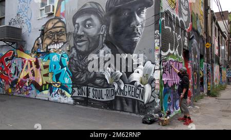 Ein Mann, der Graffiti an die Wand sprüht in Toronto, Ontario, Kanada Stockfoto