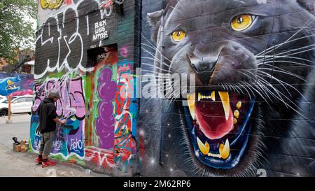 Ein Mann, der Graffiti auf eine Stadtmauer in Toronto, Ontario, Kanada, spritzt Stockfoto