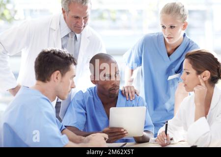 Besprechen der besten Behandlung für einen Patienten. Eine Gruppe von Ärzten, die sich unterhalten. Stockfoto
