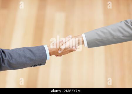 Lass uns den Deal besiegeln. Abgeschnittenes Bild von zwei Führungskräften, die sich im Kopierraum die Hände schütteln. Stockfoto