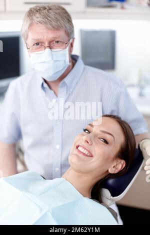 Arzt mit lächelndem Patienten. Das Porträt eines reifen Arztes mit lächelndem Patienten in der Klinik. Stockfoto
