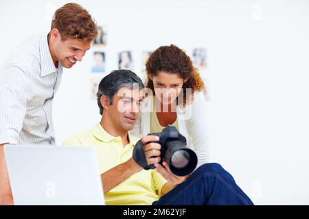 Fotografen, die Fotos in der Kamera ansehen. Fotograf, der seinen Kollegen Fotos in seiner Kamera zeigt. Stockfoto