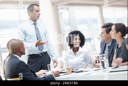 Ich denke, wir hatten ein wunderbares Jahr finanziell. Eine vielfältige Gruppe von Geschäftsleuten, die während eines Meetings von ihrem Vorgesetzten angesprochen werden. Stockfoto