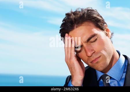 Gestresster junger Geschäftsmann, der Zeit im Freien verbringt. Nahaufnahme eines gestressten jungen Geschäftsmanns, der Zeit im Freien verbringt. Stockfoto