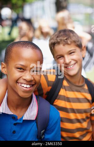 Wir sind dieses Jahr beste Freunde geworden. Zwei Schuljungen, die beste Freunde sind und draußen für ein Foto posieren - Werbespot. Stockfoto