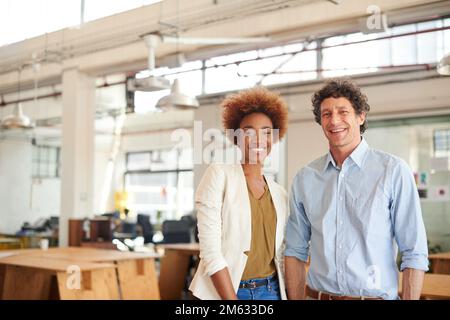 Zusammen gewinnen wir. Porträt von zwei Kollegen, die in einem Büro stehen. Stockfoto